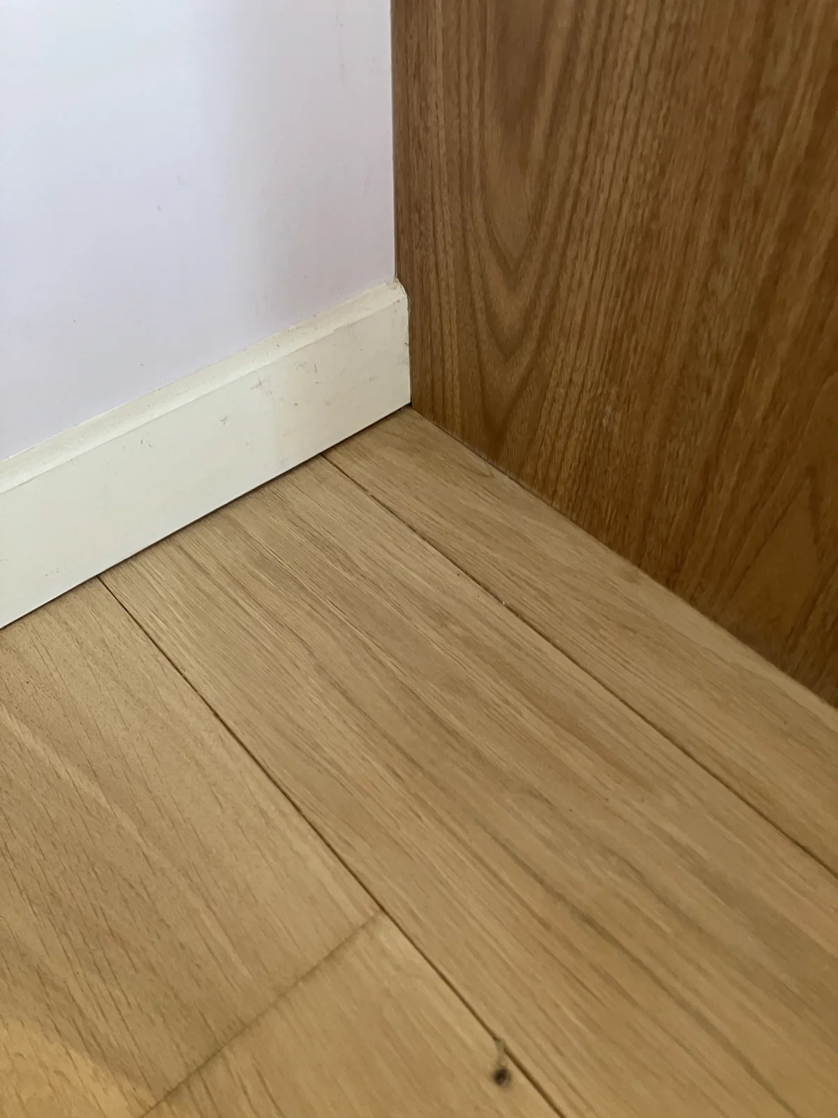 L'angle terminé : parquet poncé au ras de la plinthe et du panneau, sans bande sombre résiduelle