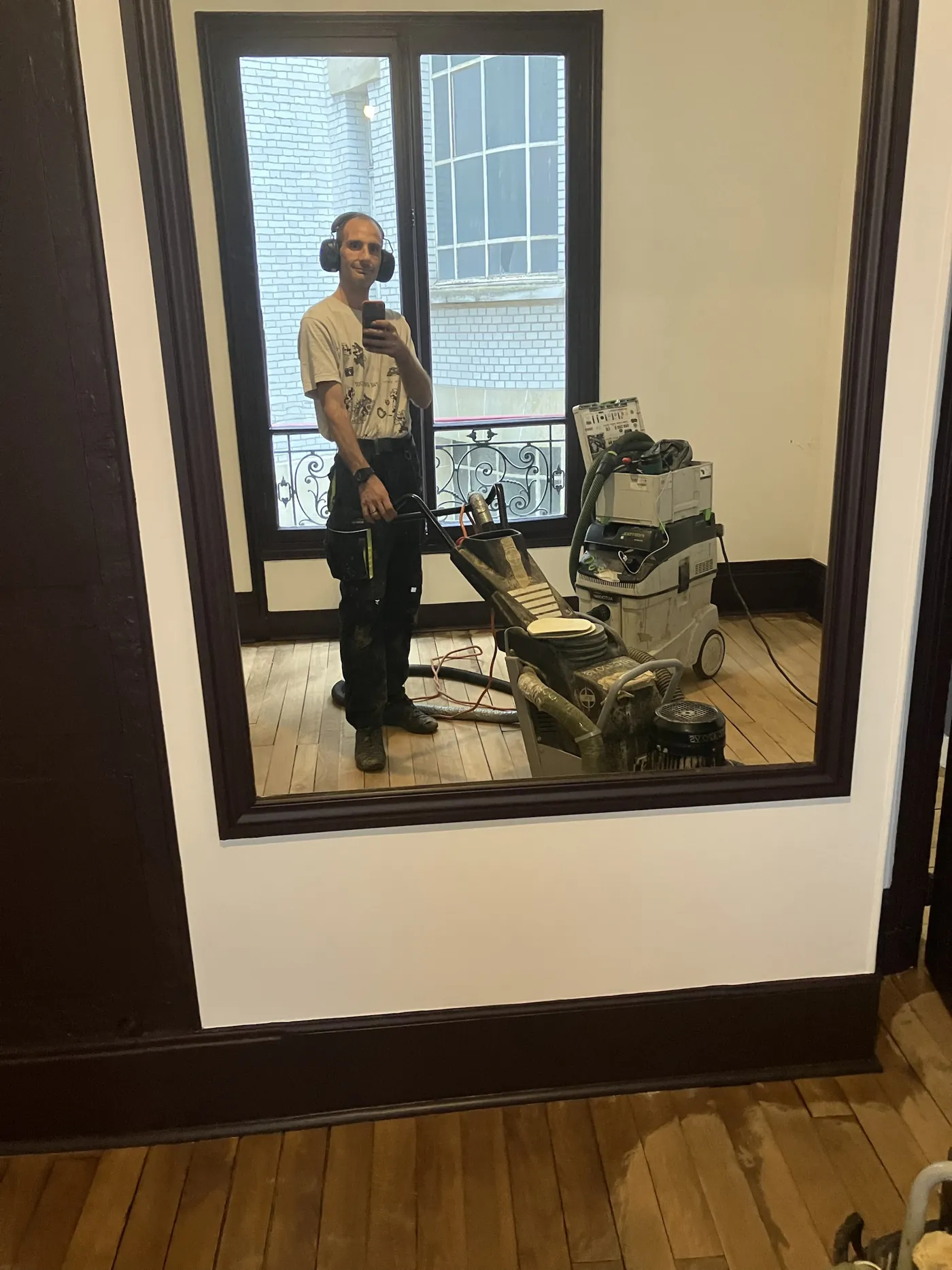 François Gaillard, artisan parqueteur indépendant, en plein ponçage d'un parquet haussmannien à Paris avec machine planétaire HTC et aspiration Festool HEPA
