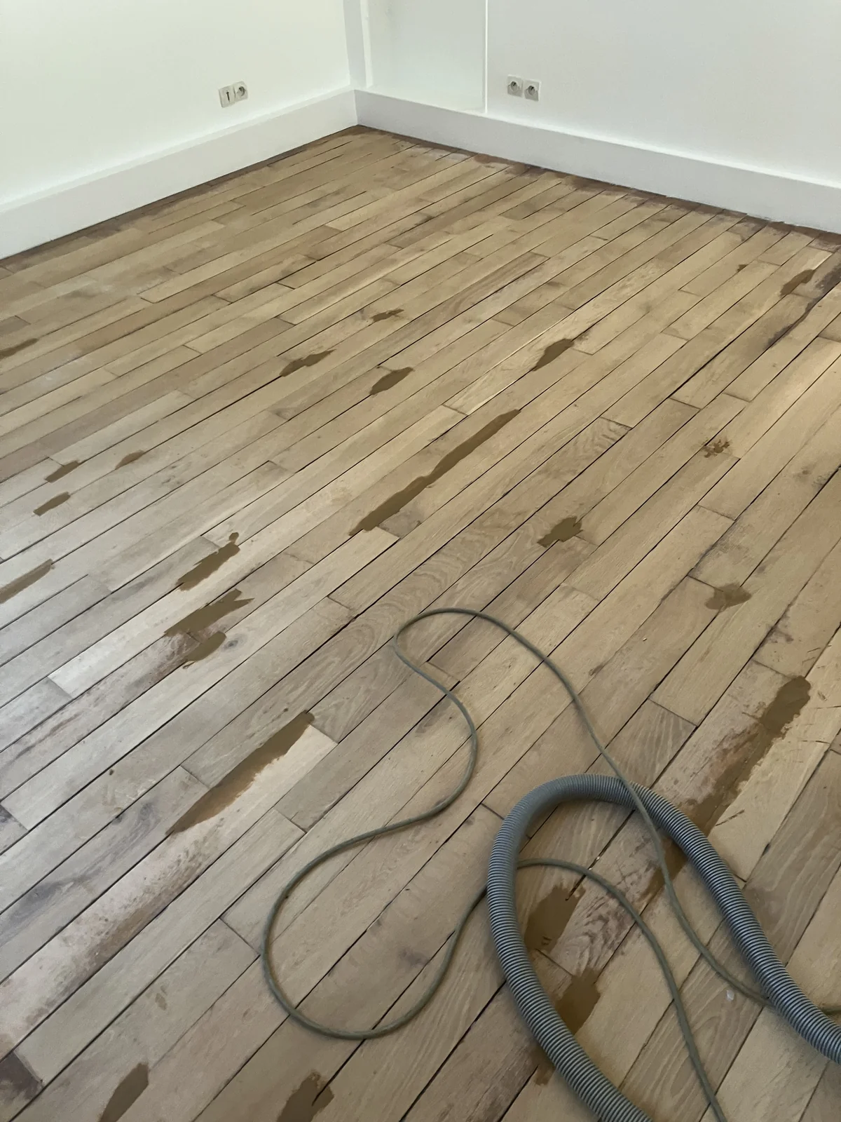 Le parquet poncé, constellé de pâte à bois : chaque manque, chaque éclat repris. Tout disparaîtra au ponçage de finition.