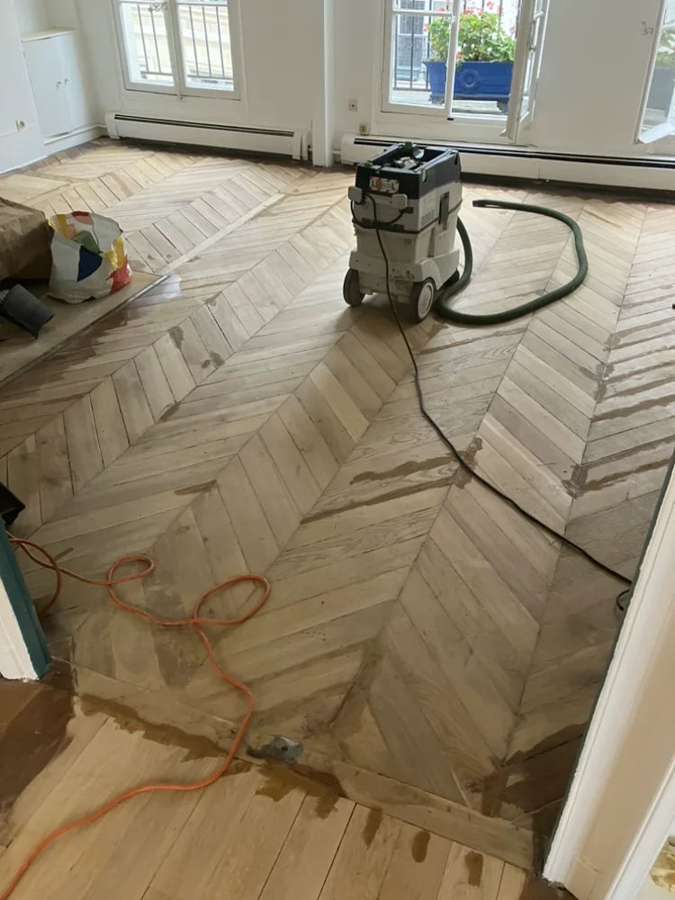 Aspiration Festool à filtre HEPA branchée sur la machine. Sur un motif en chevrons, chaque changement de sens des lames est un piège pour une ponceuse à tambour.
