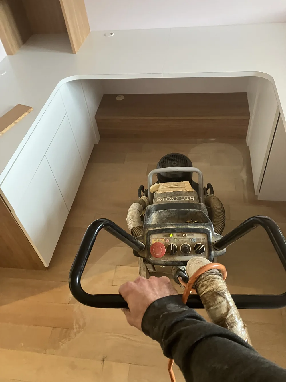 Le ponçage ne s'arrête pas au milieu de la pièce. Sous les meubles de cuisine, contre les plinthes, dans les recoins — la machine va aussi loin que sa taille le permet.