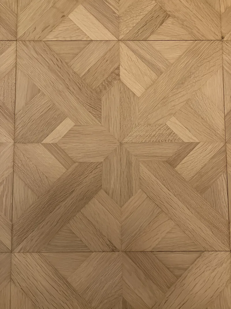 Détail de la marqueterie géométrique en chêne poncée à Garches — motif en étoile et croix