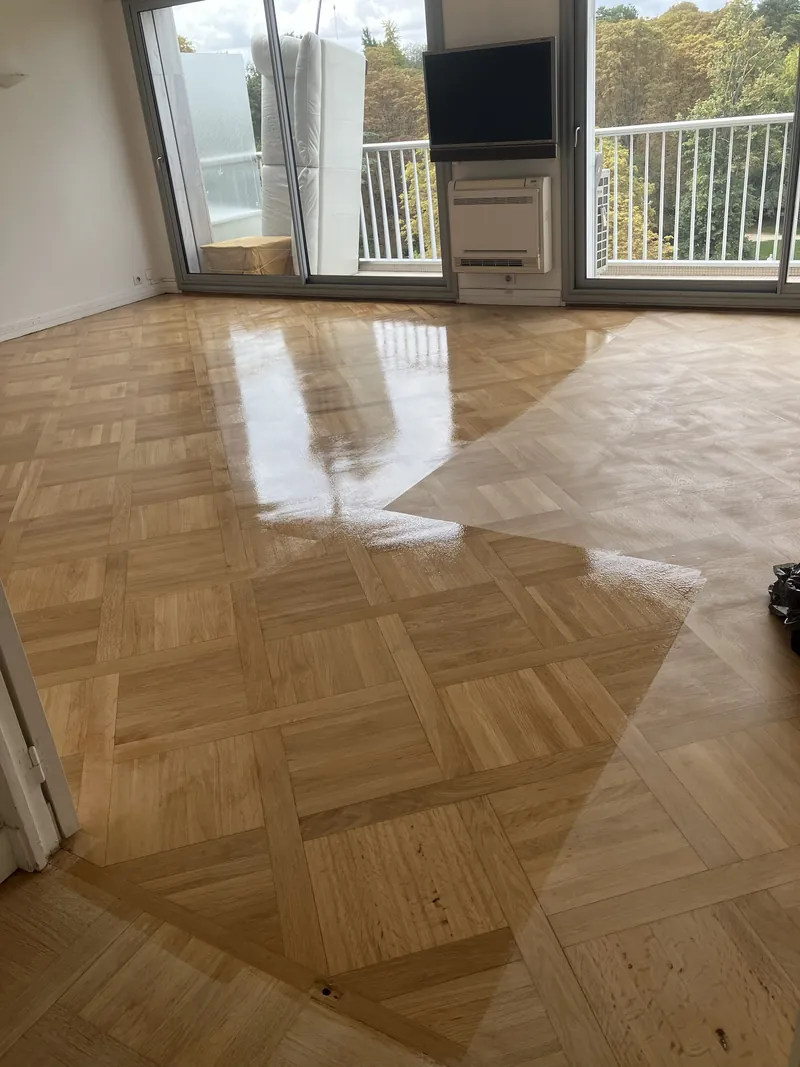 Vitrification en cours d'un parquet mosaïque chêne à Montsouris, Paris 13e — vernis frais brillant sur la moitié gauche